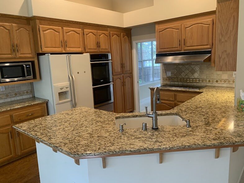 Oak cabinet kitchen with granite peninsula and polished appliances after a Scrub Bros clean